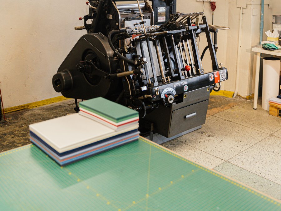 Trimmed stock stacked on a cutting mat beside the guillotine
